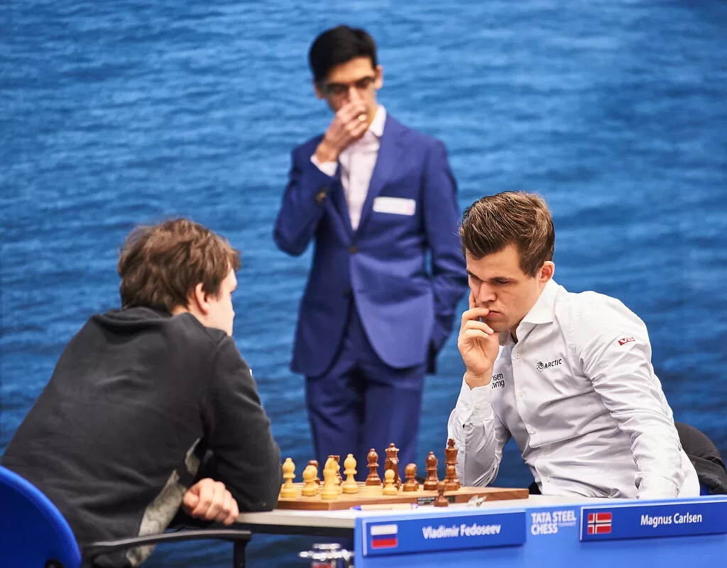 Top 100 chess players - Magnus Carlsen playing chess and Fabiano Caruana watching